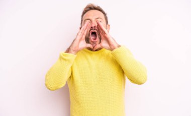 Orta yaşlı yakışıklı adam mutlu, heyecanlı ve pozitif hissediyor. Elleri ağızda, bağırıyor.