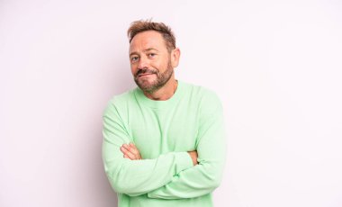 Orta yaşlı yakışıklı adam omuz silkiyor, kafası karışık ve kararsız, kolları bağlı ve şaşkın görünüyor.