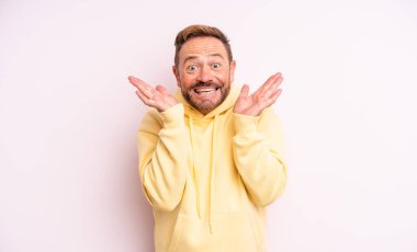 Orta yaşlı yakışıklı adam mutlu ve heyecanlı görünüyor. Beklenmedik bir sürprizle şoke olmuş. İki eli de açık.