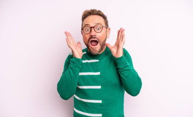 Orta yaşlı yakışıklı bir adam beklenmedik bir sürpriz yüzünden şaşkın, heyecanlı, gülen, şaşkın ve mutlu hissediyor.