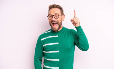 Orta yaşlı yakışıklı bir adam bir fikri fark ettikten sonra mutlu ve heyecanlı bir dahi gibi hissediyor, neşeli bir şekilde parmağını kaldırıyor, eureka!
