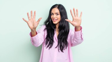 Güzel İspanyol kadın gülümsüyor ve arkadaş canlısı görünüyor, onuncu ya da onuncu numarayı gösteriyor, eli önde, geri sayıyor.