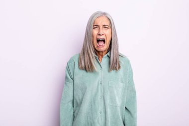 Orta yaşlı beyaz saçlı kadın agresif bir şekilde bağırıyor, kızgın, sinirli, sinirli ya da sinirli görünüyor, bağırmıyor.