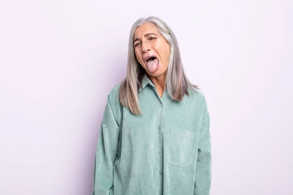 陽気で屈託のない反抗的な態度冗談を言いながら舌を出す中年の白髪の女性 — ストック写真