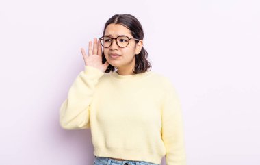 Güzel genç bir kadın ciddi ve meraklı görünüyor, dinliyor, gizli bir konuşma veya dedikodu duymaya çalışıyor, kulak misafiri oluyor.