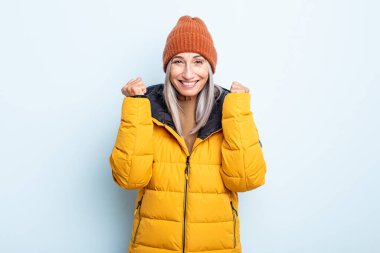 Orta yaşlı beyaz saçlı kadın şokta, gülüyor ve başarıyı kutluyor. Soğuk hava kavramı