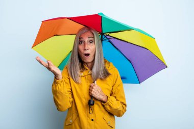 Orta yaşlı, gri saçlı kadın şok olmuş ve şaşırmış hissediyor. şemsiye ve yağmur kavramı