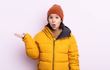 Güzel, genç bir kadın şaşırmış ve şok olmuş görünüyor. Çenesi düşmüş, elinde bir nesne var. Soğuk hava kavramı