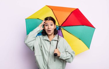 Güzel, genç bir kadın mutlu, şaşkın ve şaşırmış görünüyor. yağmur ve şemsiye kavramı