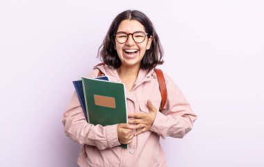 Güzel genç bir kadın komik bir şakaya yüksek sesle gülüyor. Kitap konsepti olan öğrenci