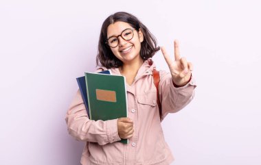 Gülümseyen ve mutlu görünen güzel genç bir kadın zafer ya da barış işareti yapıyor. Kitap konsepti olan öğrenci