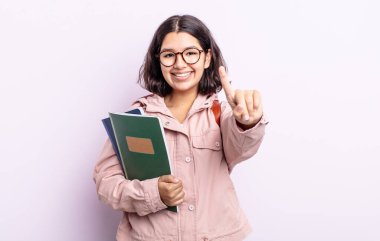 Güzel genç bayan gülümsüyor ve arkadaş canlısı görünüyor, bir numarayı gösteriyor. Kitap konsepti olan öğrenci