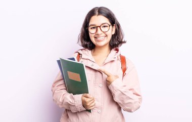 Güzel, genç bir bayan neşeyle gülümsüyor, mutlu hissediyor ve bir tarafı işaret ediyor. Kitap konsepti olan öğrenci