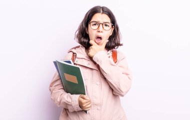 Ağzı ve gözleri sonuna kadar açık ve eli çenesinde güzel genç bir kadın. Kitap konsepti olan öğrenci