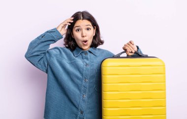 Güzel, genç bir kadın mutlu, şaşkın ve şaşırmış görünüyor. seyahat çantası kavramı