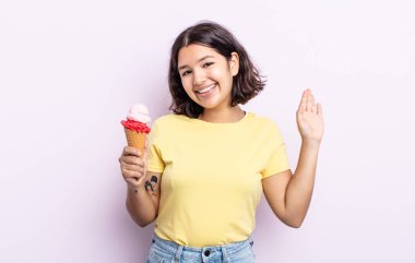 Güzel, genç bir bayan mutlu bir şekilde gülümsüyor, el sallıyor, sizi selamlıyor ve selamlıyor. dondurma konsepti