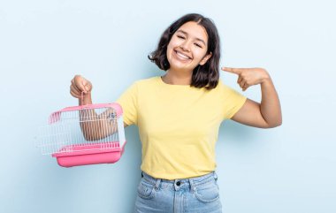 Kendine güvenen güzel genç bir kadın kendi gülüşünü işaret ediyor. evcil hayvan kafesi