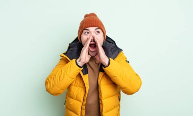 Genç yakışıklı adam mutlu hissediyor, elleri ağzının kenarında bağırıyor. Soğuk hava kavramı