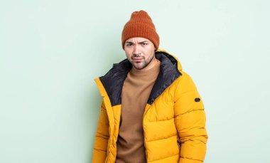 Genç ve yakışıklı bir adam üzgün, üzgün ya da kızgın hissediyor ve yan tarafa bakıyor. Soğuk hava kavramı