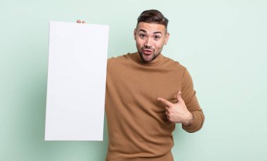 Genç ve yakışıklı bir adam mutlu hissediyor ve heyecanla kendini işaret ediyor. boş tuval kavramı