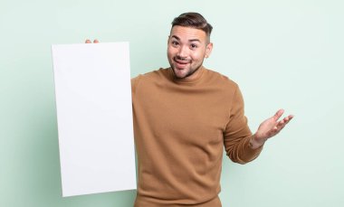 young handsome man feeling happy, surprised realizing a solution or idea. empty canvas concept