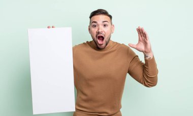 young handsome man screaming with hands up in the air. empty canvas concept