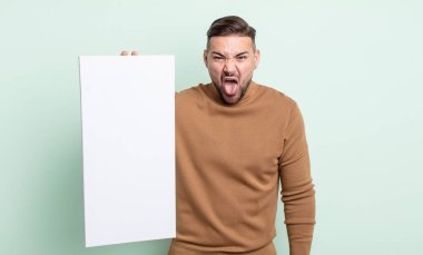 young handsome man feeling disgusted and irritated and tongue out. empty canvas concept