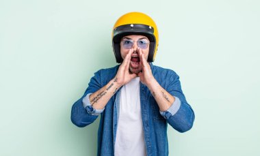 Genç yakışıklı adam mutlu hissediyor, elleri ağzının kenarında bağırıyor. Motosiklet kaskı konsepti