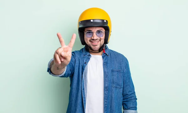 若いハンサムな男は笑顔で友好的に見える2番目を示しています バイクヘルメットのコンセプト — ストック写真