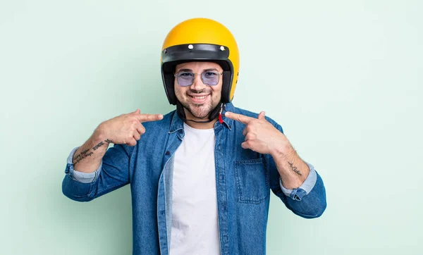 若いハンサムな男は自信を持って笑顔を指す バイクヘルメットのコンセプト — ストック写真