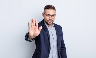 Genç ve yakışıklı adam ciddi görünüyor. Avuç içi gösteriyor. Durdurma hareketi yapıyor. İş adamı konsepti