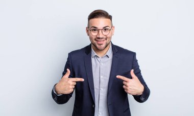 Genç ve yakışıklı bir adam mutlu hissediyor ve heyecanla kendini işaret ediyor. İş adamı konsepti