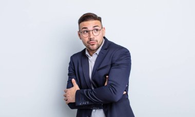 Genç yakışıklı adam omuz silkiyor, kafası karışık ve kararsız. İş adamı konsepti