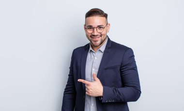 Genç yakışıklı adam neşeyle gülümsüyor, mutlu hissediyor ve bir tarafı işaret ediyor. İş adamı konsepti