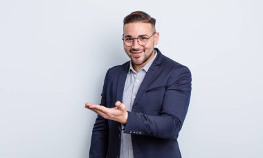 Genç yakışıklı adam neşeyle gülümsüyor, mutlu hissediyor ve bir konsept gösteriyor. İş adamı konsepti