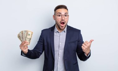 İnanamadığı için şaşırmış genç ve yakışıklı bir adam. Dolar banknotları konsepti
