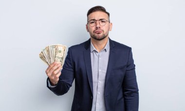 Genç ve yakışıklı bir adam üzgün ve mızmızlanıyor. Mutsuz bir bakışı var ve ağlıyor. Dolar banknotları konsepti