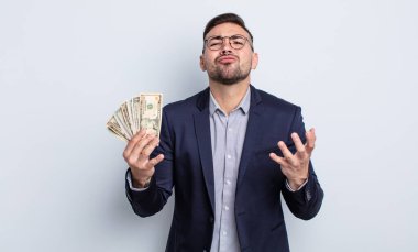 Genç yakışıklı adam umutsuz, sinirli ve stresli görünüyor. Dolar banknotları konsepti