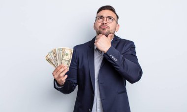 Genç yakışıklı düşünen, kuşkulu ve kafası karışık bir adam. Dolar banknotları konsepti