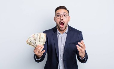 Genç ve yakışıklı bir adam şok olmuş ve şaşırmış hissediyor. Dolar banknotları konsepti