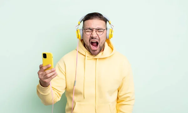 Młody Przystojny Mężczyzna Krzyczący Agresywnie Wyglądający Wściekłego Słuchawki Koncepcja Smartfona — Zdjęcie stockowe