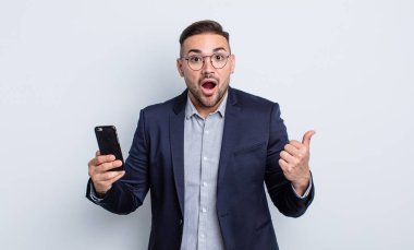 İnançsızlığa ve akıllı telefon kavramına hayret eden genç yakışıklı bir adam.