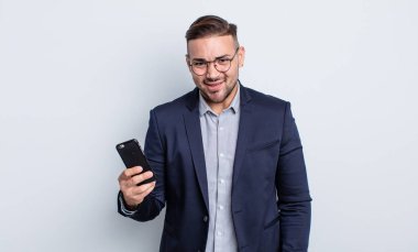 Genç yakışıklı adam kafası karışmış, kafası karışmış iş ve akıllı telefon kavramı