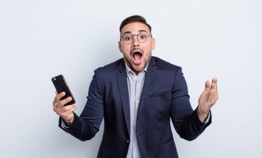 Genç ve yakışıklı adam son derece şaşkın ve şaşkın iş ve akıllı telefon kavramı hissediyor.