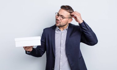 Genç yakışıklı adam mutlu bir şekilde gülümsüyor ve hayal kuruyor ya da şüphe ediyor. beyaz kutu kavramı