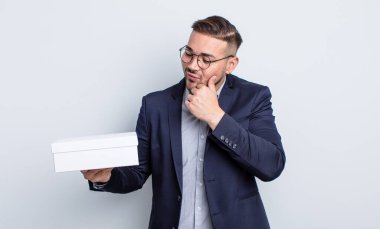 Genç ve yakışıklı bir adam mutlu ve kendinden emin bir ifadeyle gülümsüyor, elleri çenesinde. beyaz kutu kavramı