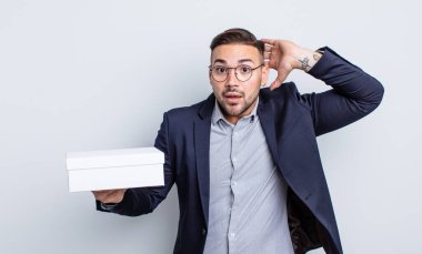 Genç ve yakışıklı bir adam stresli, endişeli ya da korkmuş hissediyor. Elleri başının üstünde. beyaz kutu kavramı