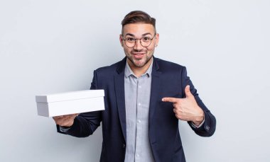 Genç ve yakışıklı bir adam mutlu hissediyor ve heyecanla kendini işaret ediyor. beyaz kutu kavramı