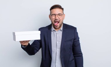 Genç, yakışıklı, neşeli ve asi tavırlı, şaka yapan ve dilini dışarı çıkaran bir adam. beyaz kutu kavramı