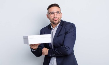 Genç yakışıklı adam omuz silkiyor, kafası karışık ve kararsız. beyaz kutu kavramı